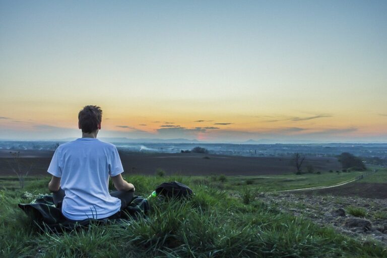 Jeune homme assis sereinement face au coucher de soleil, symbole de calme pour réviser la philo sans paniquer